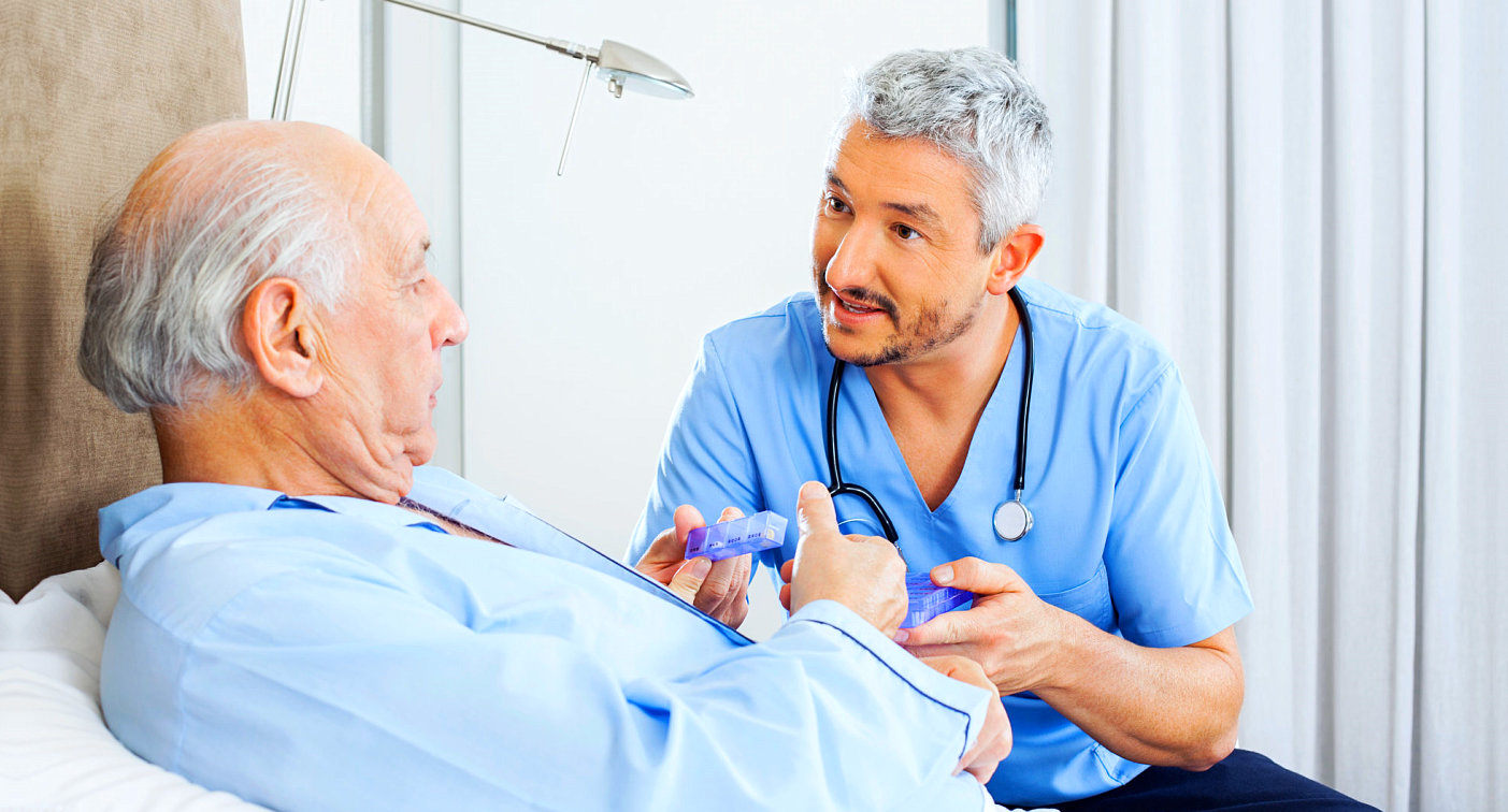 caregiver giving medicine to senior man